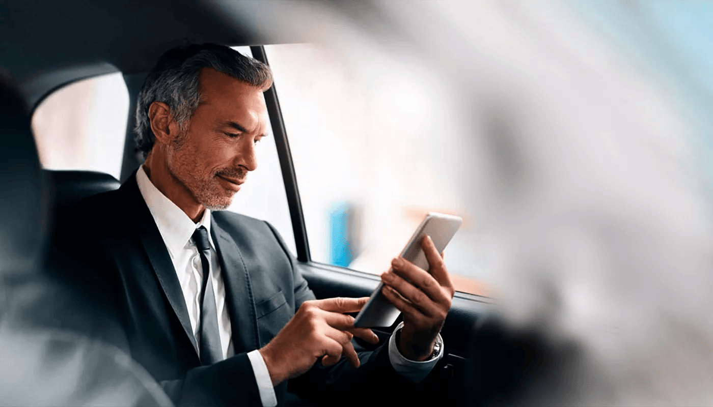 ejecutivo elegante revisando el celular mientras viaja en taxi
