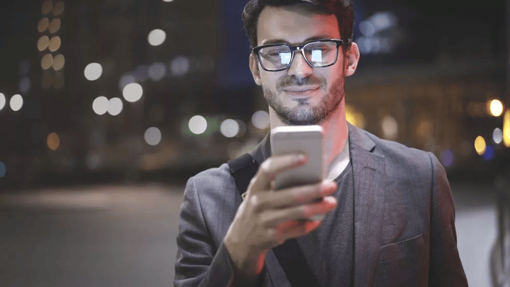 joven de lentes mirando celular